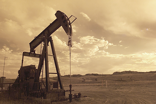 Oil rig in large field, sepia toned