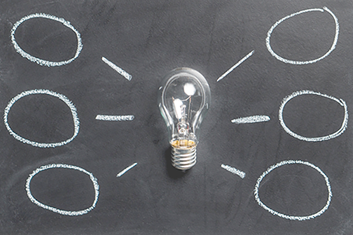 Lightbulb on a blackboard with chalk circles drawn around it.