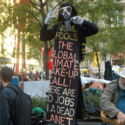 person in an elaborate costume at a protest, saying "there are no jobs on a dead planet"