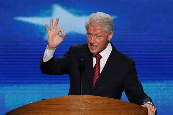 Bill Clinton at a podium, making an "OK" sign